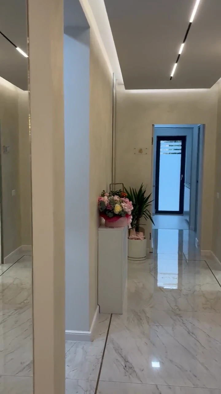 Coridorul clinicii, cu pardoseală de marmură și buchet pe consolă la capăt — cadrul de deschidere al filmului.
